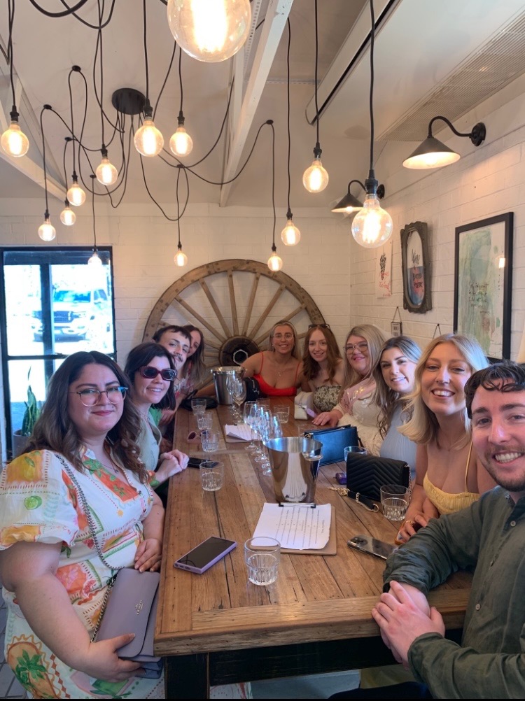Hen party enjoying drinks together around a winery table